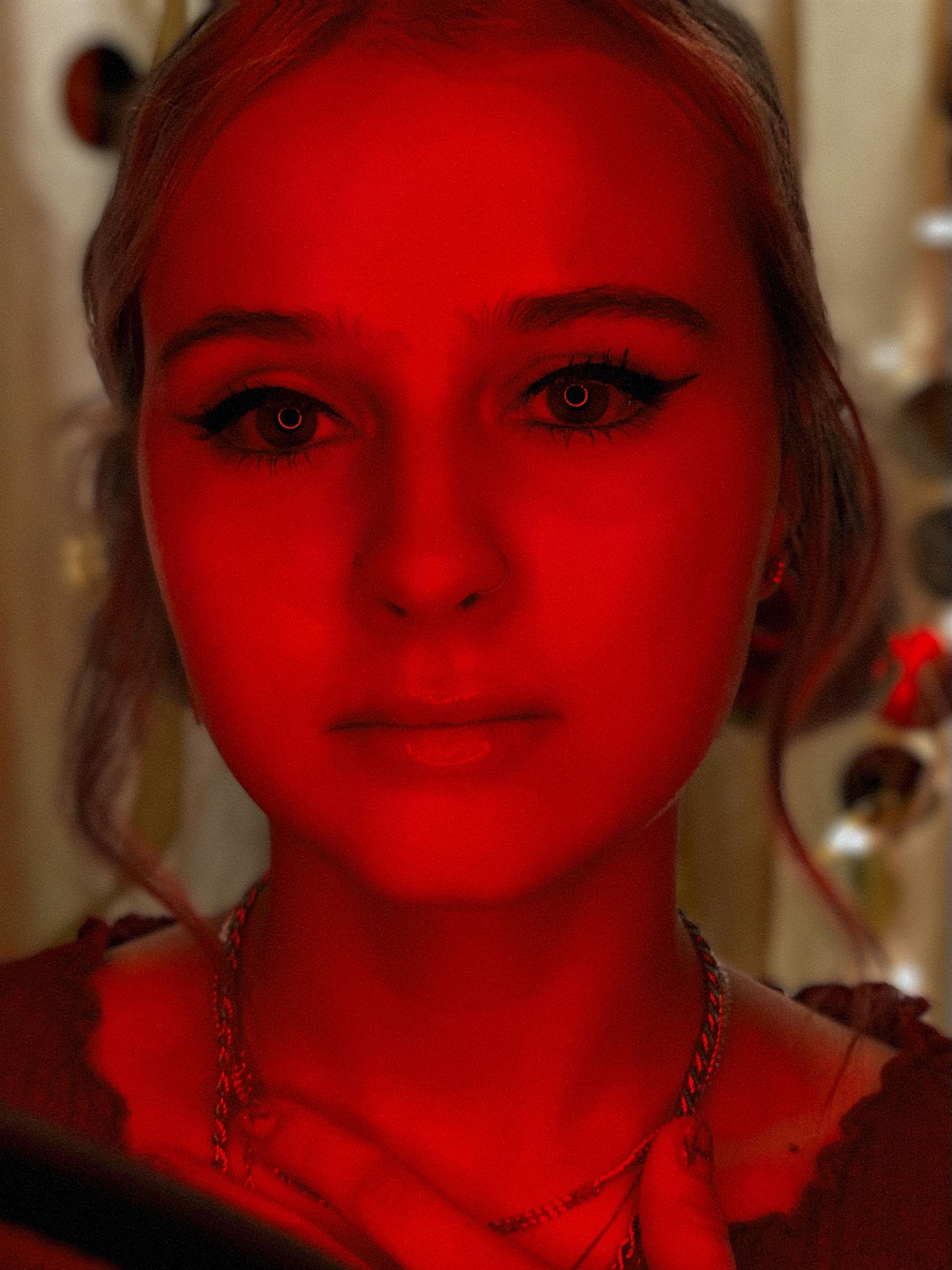 Portrait of a beautiful young woman at a Homemade Photo Booth party in a red LED light.