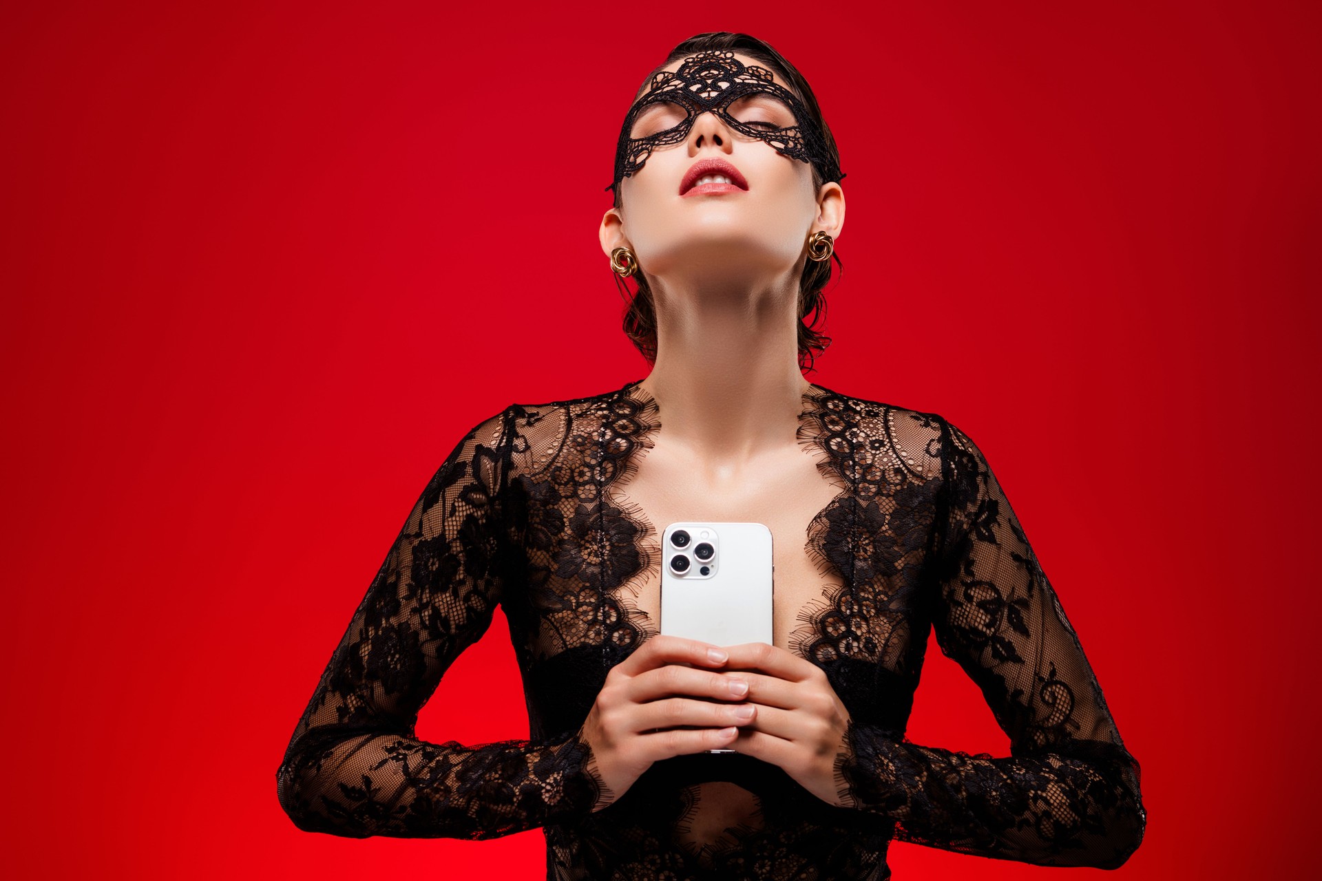 Photo of hot young woman device sensual posing dressed lace black dress mask private night party red color background