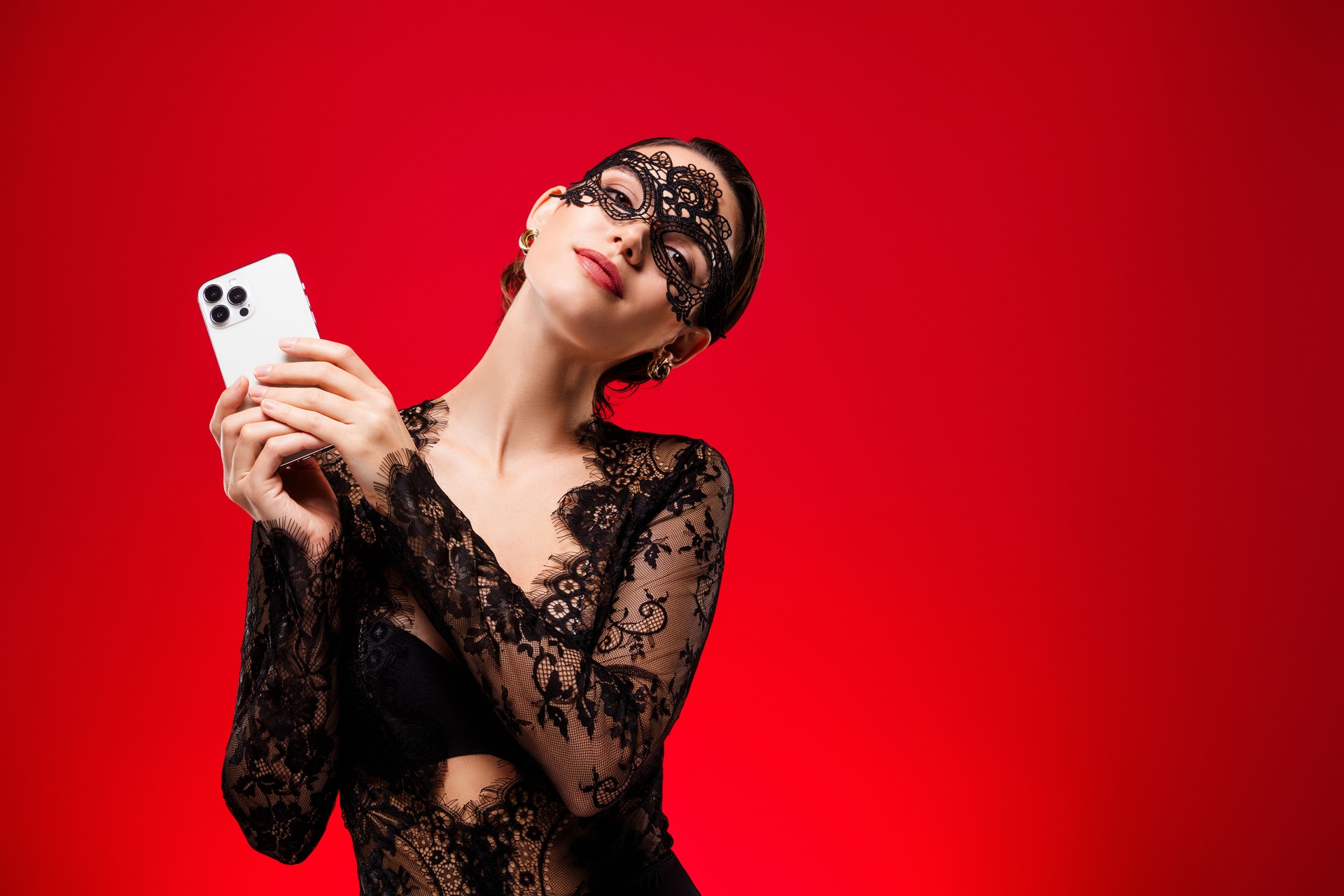 Photo of stunning hot young woman hold gadget dressed lace black dress mask private night party red color background